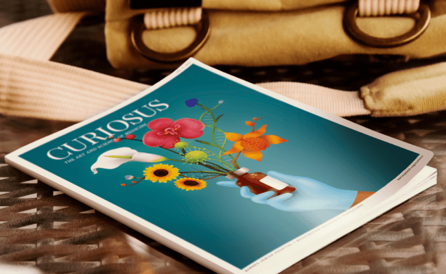 A copy of Curiosus magazine sitting on a table next to a canvas ruck sack.