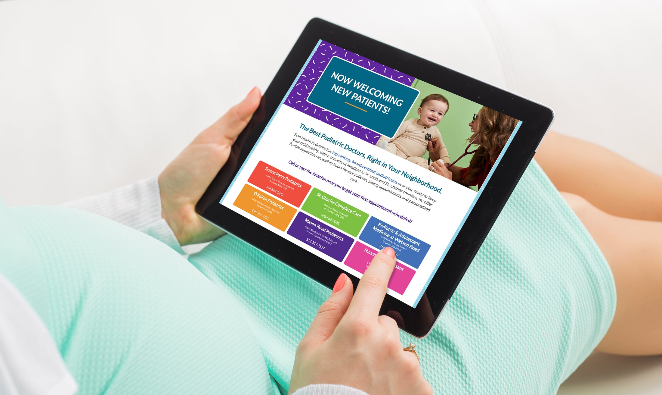 close up of pregnant person's hands holding an iPad displaying Esse Health Pediatrics webpage.